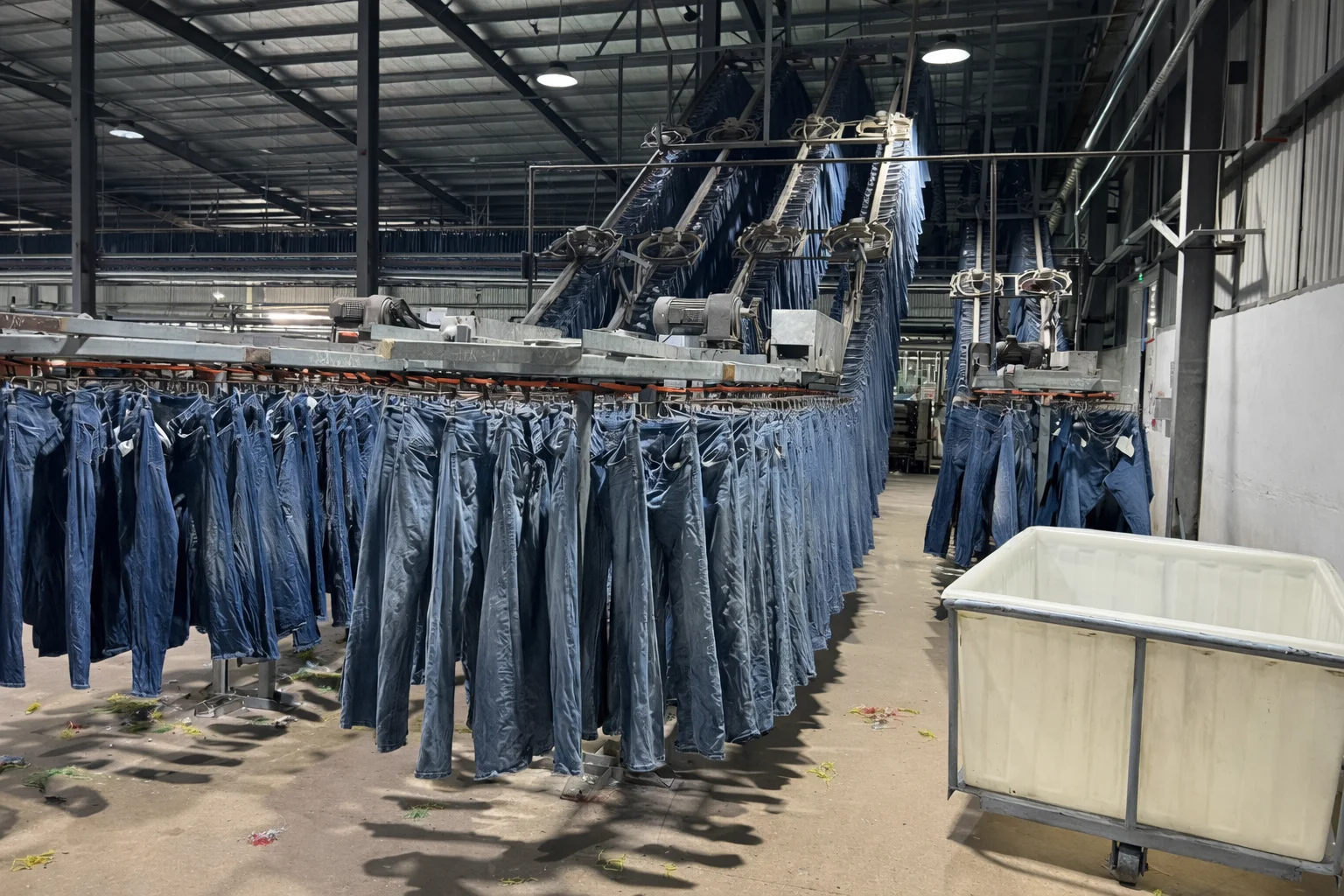 Jeans on overhead conveyor rails inside a Top Mondial factory