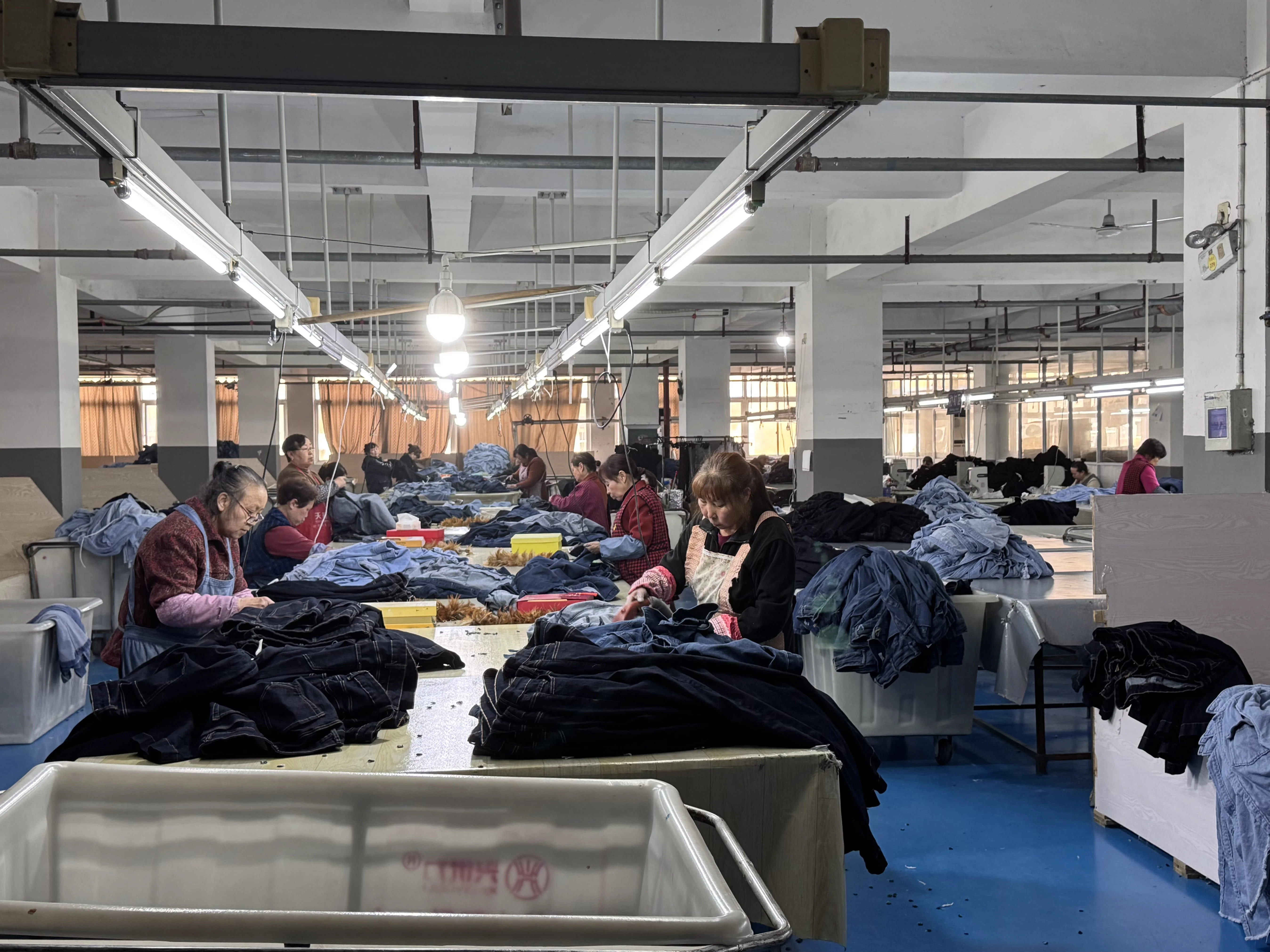 Workers sorting and handling denim garments on the production floor